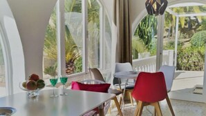 Comedor con mesa, sillas y vista a la vegetación a través de amplios ventanales.
