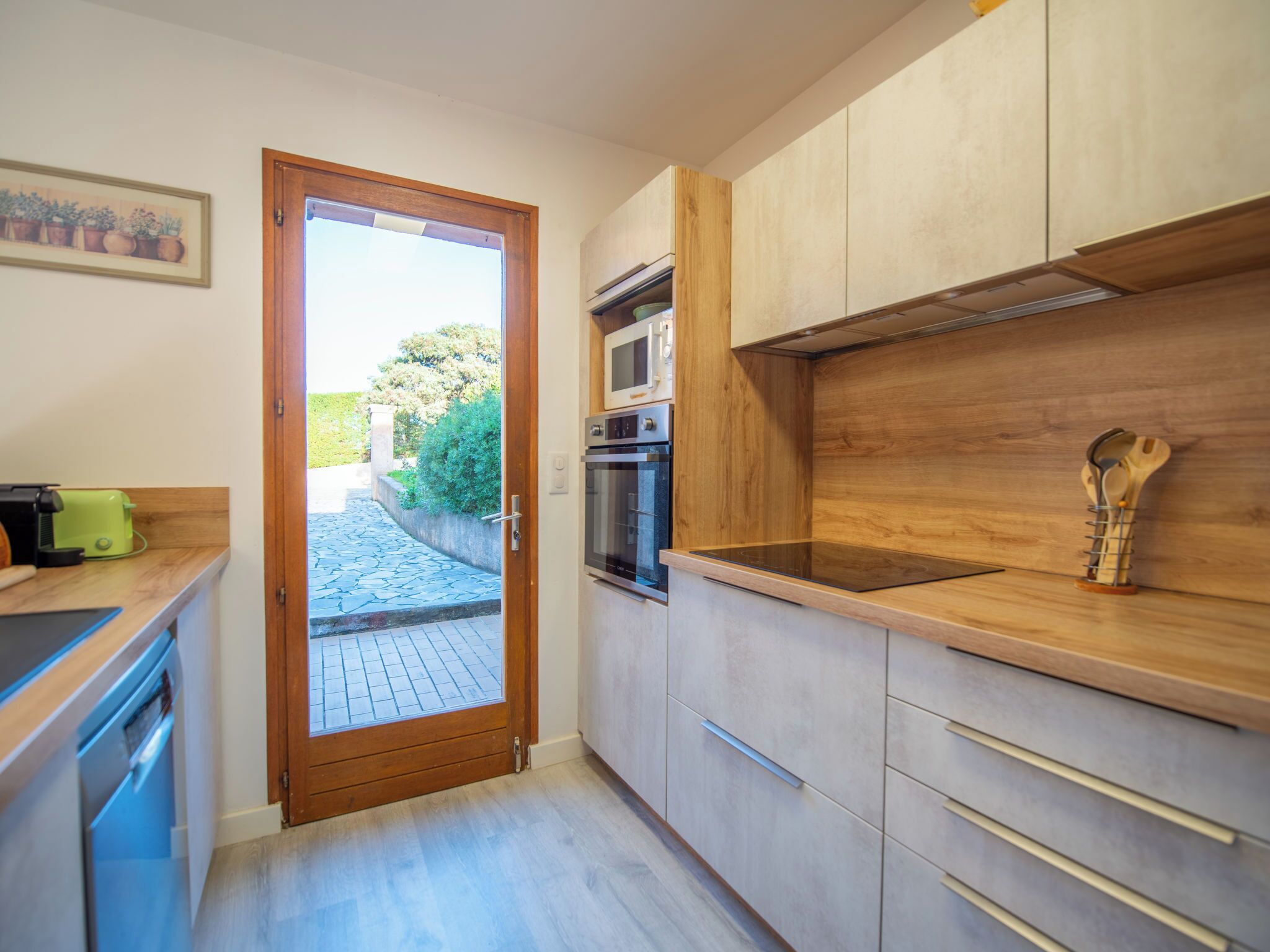 Een moderne keuken met houten kastjes, een ingebouwde oven en een groot raam.