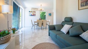 A modern living room with a green sofa, a dining table, and a chandelier. - Vacation home Vesna by Interhome (Krk/Njivice)
