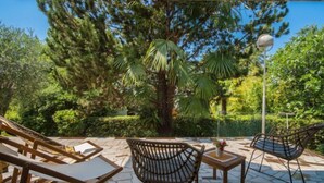 A patio area with wicker chairs and a table, surrounded by lush greenery and a clear blue sky. - Vacation home Vesna by Interhome (Krk/Njivice)