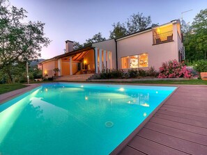 A modern house with a swimming pool, a covered patio, and a garden.