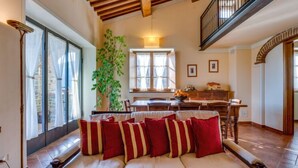 A spacious living area with a sofa, a dining table, and a staircase. - Vacation home Zen by Interhome (Castiglion Fiorentino)