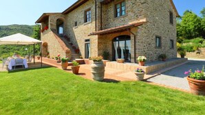 A stone building with a covered patio, outdoor seating, and potted plants. - Vacation home Zen by Interhome (Castiglion Fiorentino)