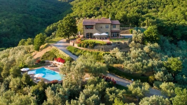 A two-story stone house with a swimming pool and outdoor seating area surrounded by dense greenery and hills. - Vacation home Zen by Interhome (Castiglion Fiorentino)