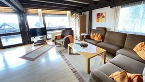 A spacious living room with a wooden ceiling, a large sofa, a coffee table, and a television. - Ferienpark Vorauf by Interhome (Siegsdorf)