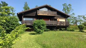 A two-story wooden house with a balcony, surrounded by lush greenery. - Ferienpark Vorauf by Interhome (Siegsdorf)
