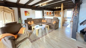A spacious living room with a brown sofa set, a wooden coffee table, and a kitchen area in the background. - Ferienpark Vorauf by Interhome (Siegsdorf)