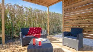 An outdoor patio with wicker furniture, a wooden table, and a red star-patterned cushion. - Les Villas de l'Etang by Interhome (Canet-Plage)