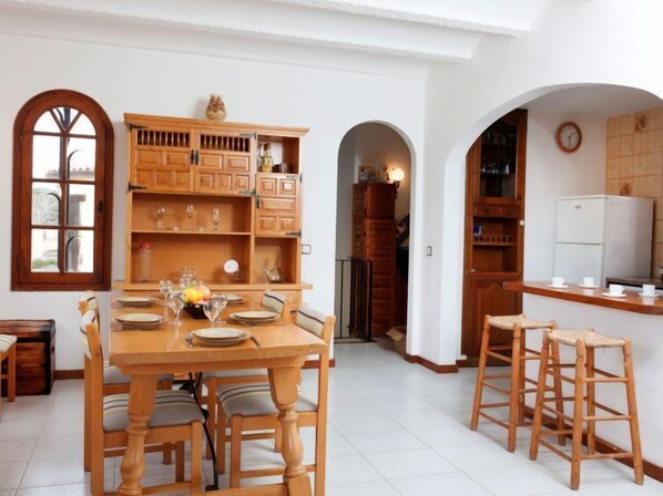 Una cocina amplia con armarios de madera, una mesa de comedor para cuatro personas y un refrigerador.