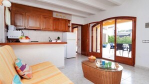 Une cuisine moderne avec des meubles en bois, un réfrigérateur blanc et un coin repas comprenant une table et des chaises en osier.