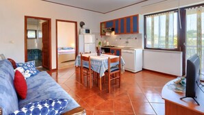 A compact living space with a kitchenette, a dining area, and a sofa with patterned cushions. - Apartment  Ana by Interhome (Porec/Jehnici)