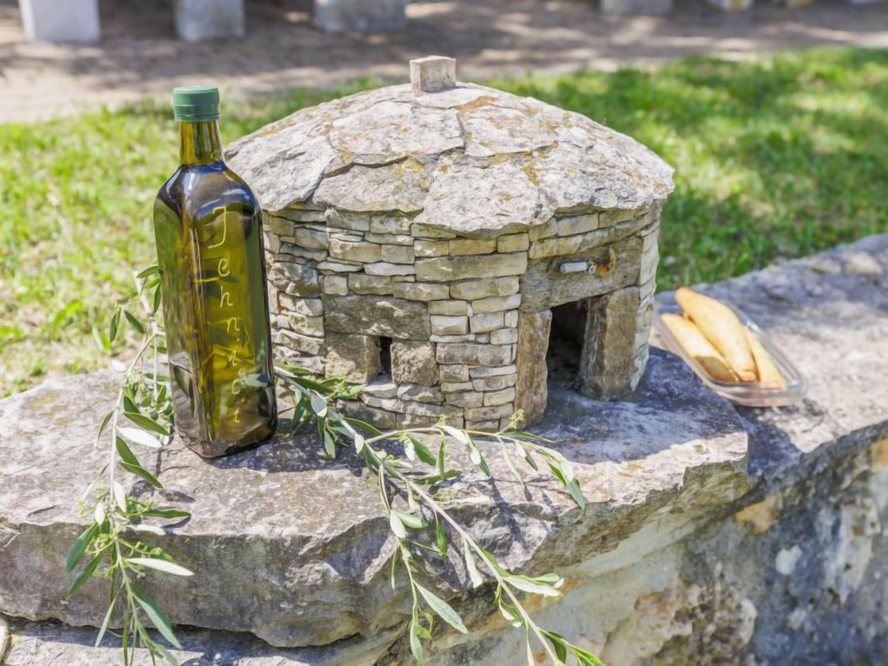 Ein steingebautes Gebilde, das einem kleinen Haus oder einem Ofen ähnelt, mit einer Flasche und Brot auf einem Felsen in der Nähe.