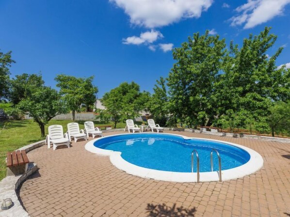 A swimming pool with a brick patio, surrounded by white lounge chairs and trees. - Apartment Ana by Interhome (Porec/Jehnici)