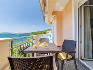 Un balcón con mesa, sillas y vista al mar.