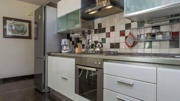 Een koelkast, een oven, een vaatwasser, kookgerei, borden en bestek