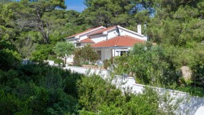 Ein Haus mit rotem Ziegeldach, umgeben von dichtem Grün und Bäumen.