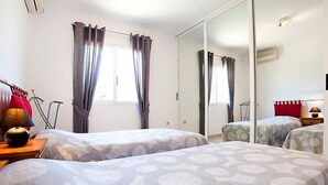 Ein Hotelzimmer mit zwei Betten, einem großen Spiegel und einem Fenster mit Vorhängen.