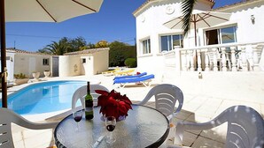 Ein Poolbereich mit Tisch, Stühlen und Sonnenschirmen.