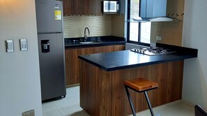 A modern kitchen with a central island, stainless steel appliances, and wooden cabinetry. - Kapital Suites (Pereira)