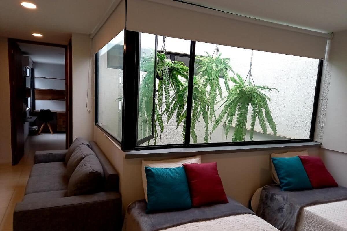 Une chambre moderne avec une grande fenêtre, un canapé, un lit et une petite table.