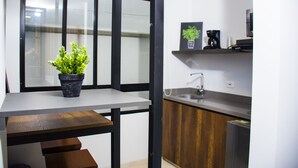 A modern kitchen with a built-in stove, a sink, and a potted plant on a window sill. - Kapital Suites (Pereira)