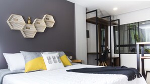 A modern bedroom with a large bed, geometric wall decor, and a view of the outdoors. - Kapital Suites (Pereira)