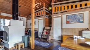 Ein rustikales Blockhaus-Interieur mit Holzbalkendecke, einem weißen Kühlschrank, einem Esstisch und einer Karte an der Wand.