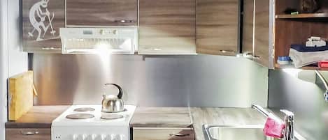 Cucina con mobili in legno, piano cottura bianco, lavello e un elemento decorativo a parete.