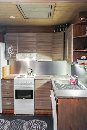A kitchen with wooden cabinets, a white stove, a sink, and a decorative wall piece.