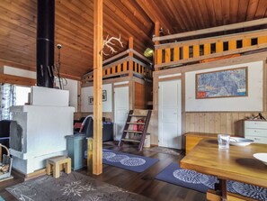 A cozy cabin interior with a wooden ceiling, a dining table, a kitchen area, and a map on the wall.