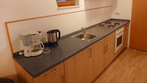 Une cuisine de taille réduite, dotée d’une fenêtre, d’un évier, d’une cuisinière et d’une machine à café.