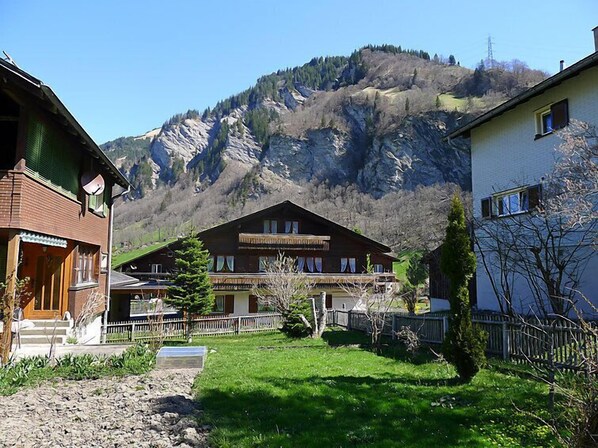 A traditional chalet with a wooden facade, a balcony, and a view of a mountainous landscape. - Untertal by Interhome (Elm)
