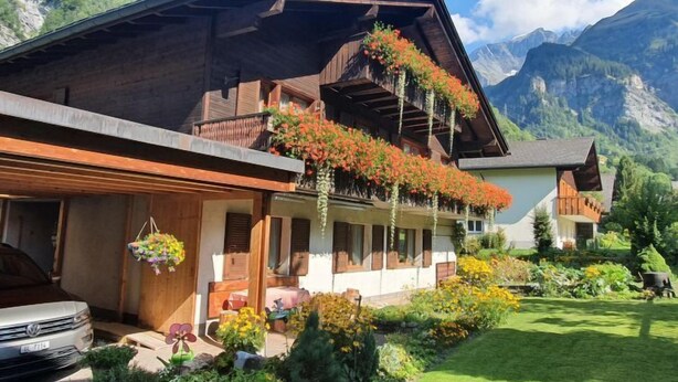 A chalet with a sloped roof, wooden balconies, and a garden with various plants and flowers. - Untertal by Interhome (Elm)