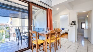 Eine moderne Wohnung mit Balkon, einem Essbereich mit Holztischen und -stühlen sowie einer Küchenzeile.