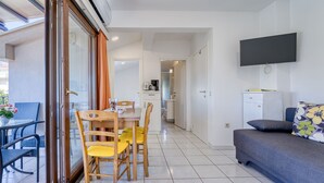 Eine moderne Wohnung mit Essbereich, Küchenzeile und Wohnzimmer mit Sofa und Fernseher.