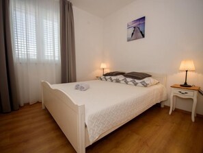 Un lit bien fait, avec des oreillers et une serviette enroulée, une table de chevet avec une lampe et un tableau accroché au mur.