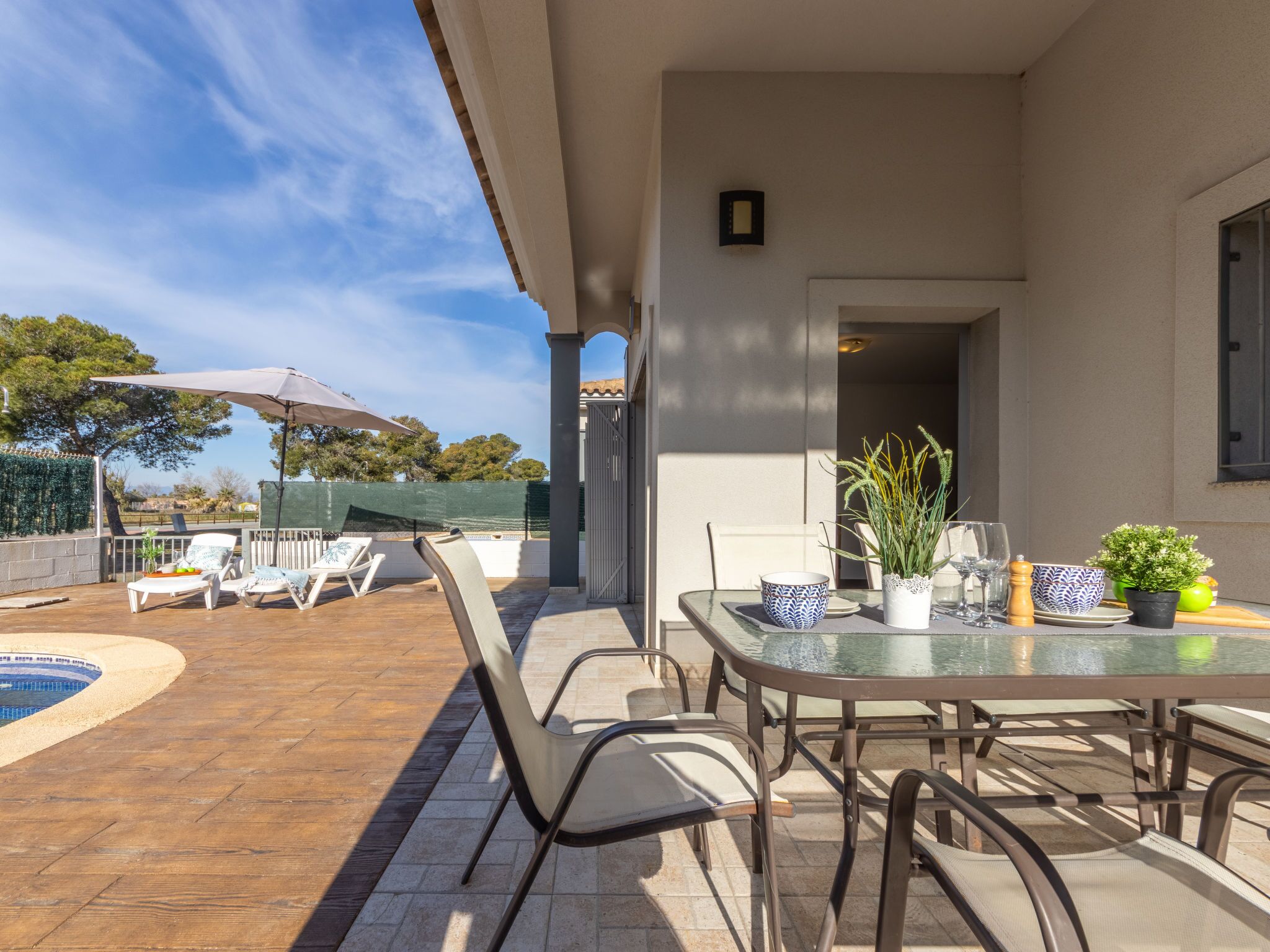 An outdoor patio with a pool, lounge chairs, and a table set for dining.