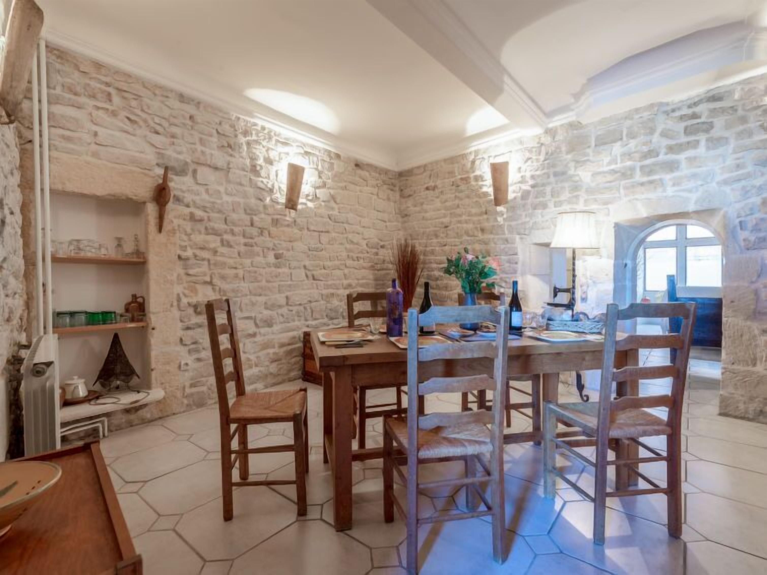Un comedor rústico con pared de piedra, mesa y sillas de madera.