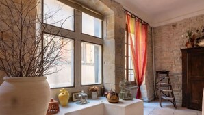 Una habitación con un ventanal grande, un florero blanco y una escalera de madera.