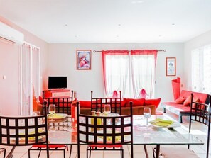 Ein modernes Wohnzimmer mit einem Glastisch, roten Sofas und einem Flachbildfernseher.