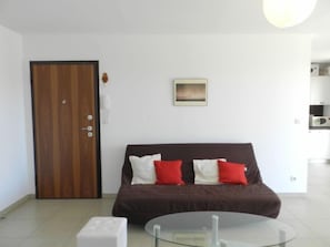 Una habitación moderna con un sofá marrón, una mesa de centro de vidrio y una puerta de madera.