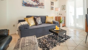 A modern living room with a grey sofa, patterned cushions, a black coffee table, and a black and white rug.