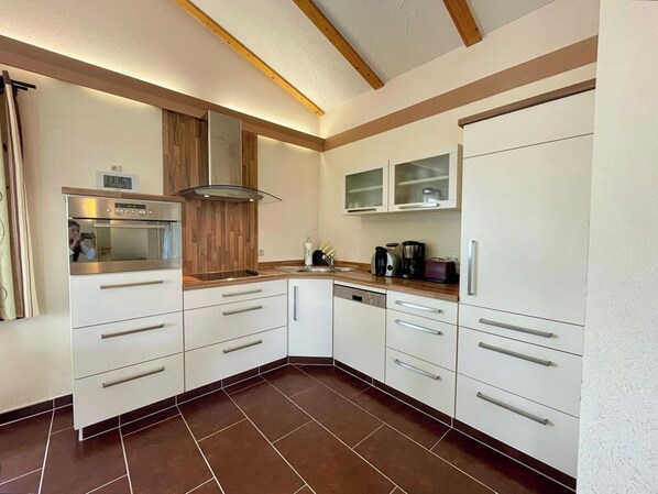 A compact kitchen with white cabinetry, a built-in oven, and a wooden countertop. - Edelmann by Interhome (Masserberg)
