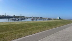 Una marina con barche ormeggiate, una zona verdeggiante e un cielo sereno.