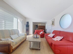 A living room with two sofas, a coffee table, and a dining area with a table and chairs.