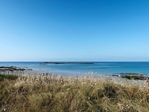 A beach with clear skies, calm water, and a distant rocky outcrop. - Sables Blancs by Interhome (Loctudy)