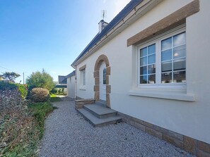 A building with a stone archway entrance, a gravel driveway, and a clear sky.