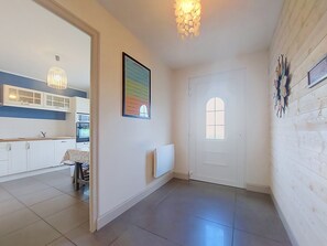 A hallway with a kitchen area on the left, a radiator, and a door with a window on the right.