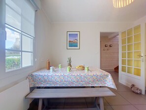Ein Zimmer mit einem Bett, einem Tisch mit Punkten, einem gerahmten Bild an der Wand und einem Fenster mit Blick nach draußen.