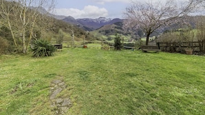 Ein grünes Feld mit einem Steinweg, Bäumen und einer entfernten Bergkette.